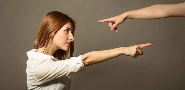 A woman pointing finger with one pointing back shows the concept of avoiding blame when trying to convince someone to go to rehab